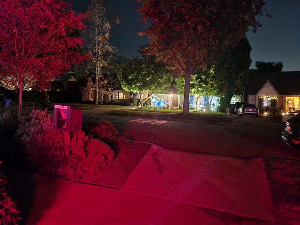 Photo from one home to another across the street at night. Of note is an 8 foot inflatable blue and white unicorn with candles from it's horn to the nape of it's neck making a menorah. The unicorn horn is the shamash candle.