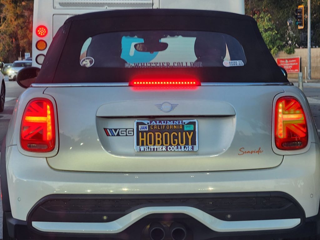 The rear of a white car with Black and Yellow California license plates which read "HOBOGUY"