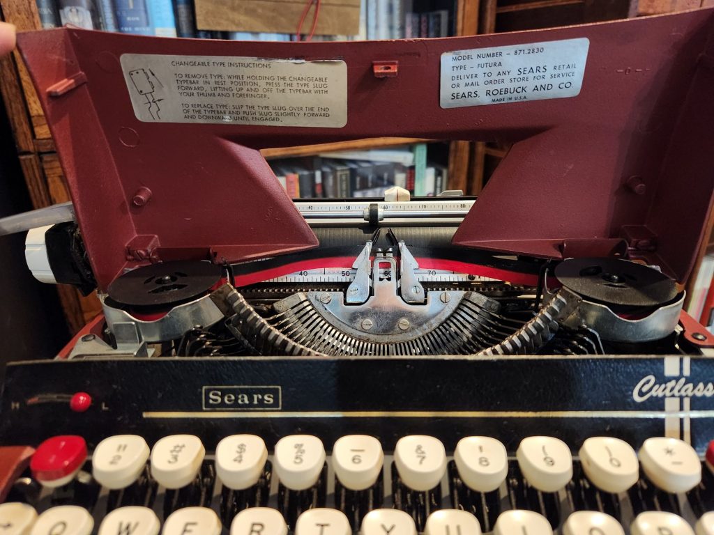 1964 Sears Cutlass with the hood open to show the stickers underneath the hood and a portion of the basket. One of the stickers indicates the type as "Futura".