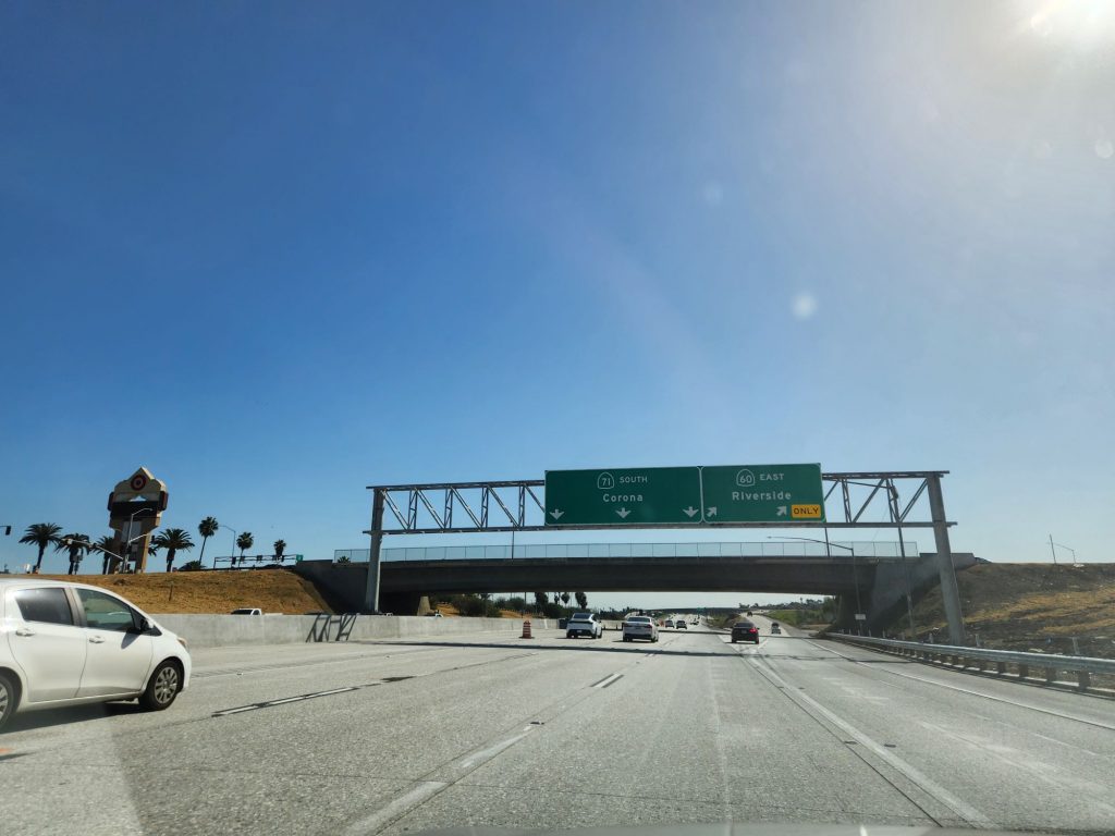 Five lane highway featuring a massive sign over the road announcing the split between the 71 South to Corona and the 60 East to Riverside.