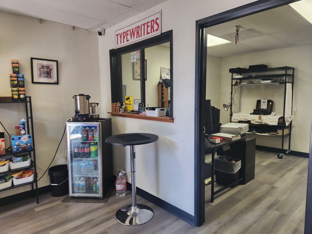 The front reception window that separates the reception and writing rooms from the office and repair space in a typewriter shop.