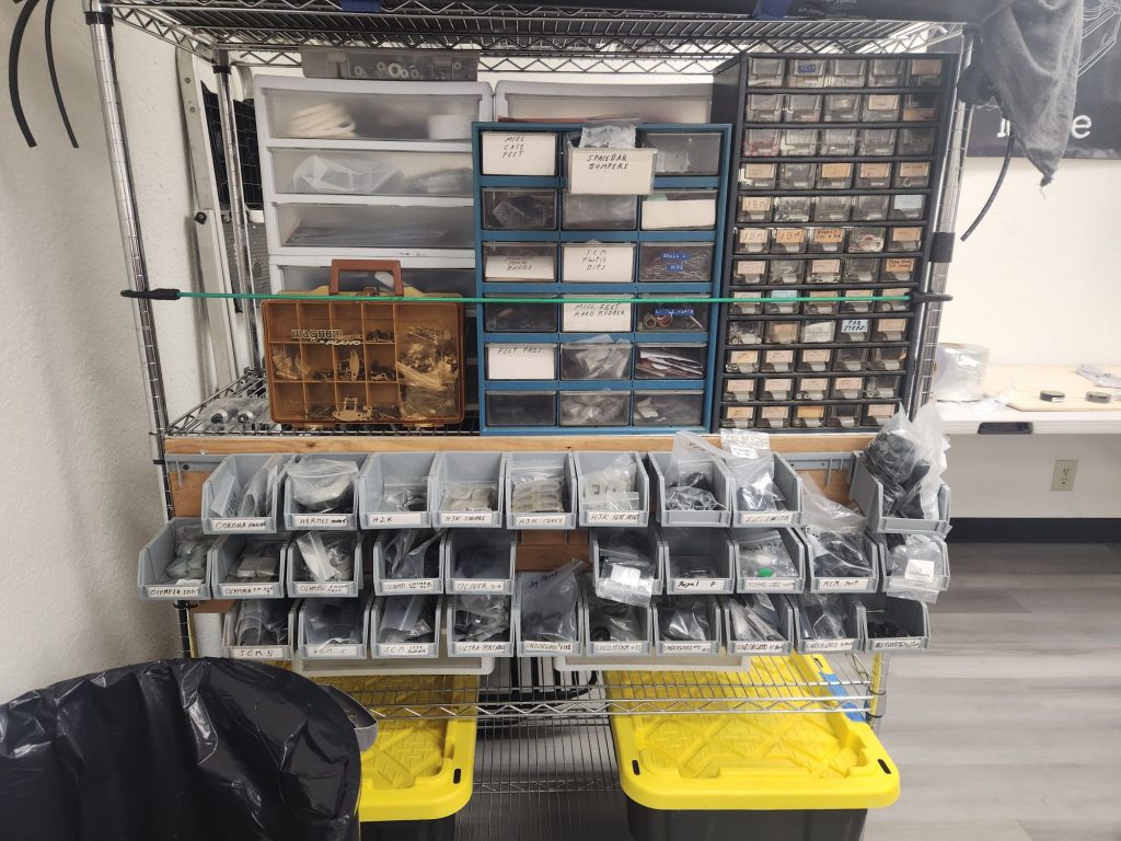 A parts station with shelving for a variety of typewriter replacement feet, and miniature drawers for screws, springs, and various other typewriter parts.