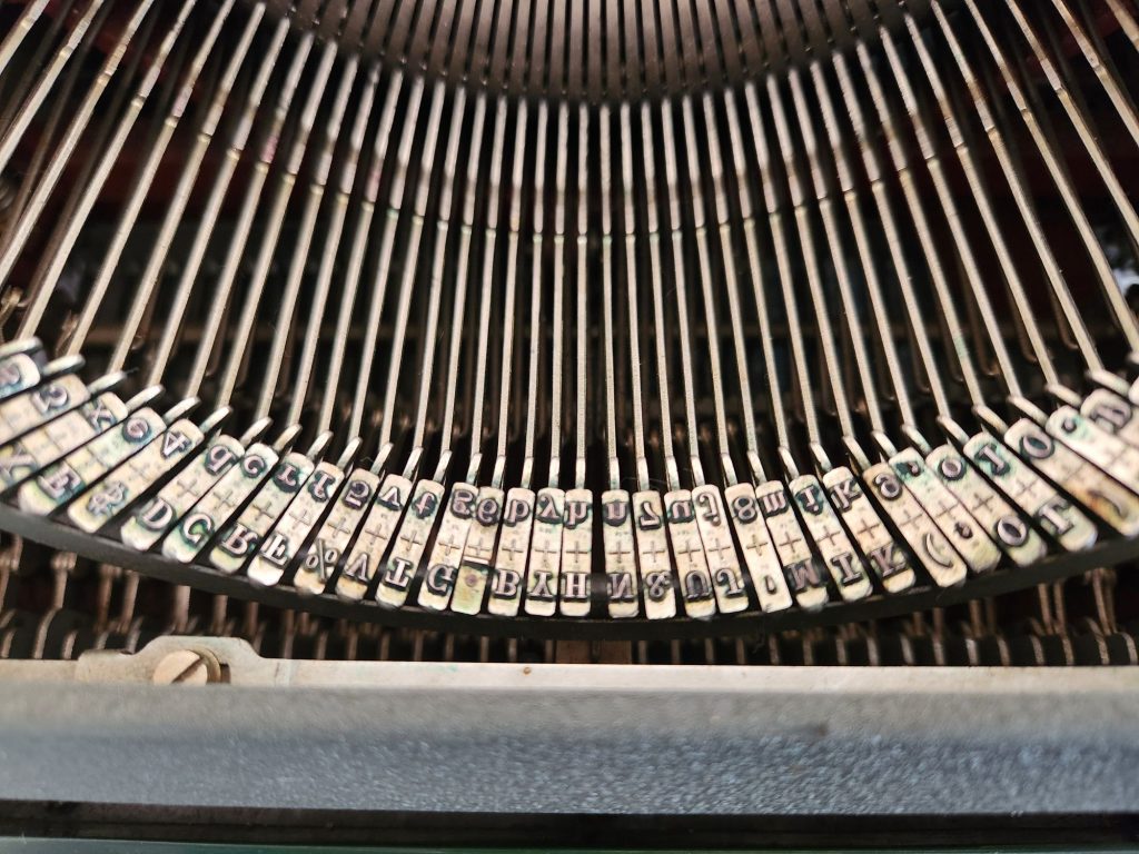 Congress Elite No. 84 typeface on slugs in a close up of the segment of an Olympia SG1 typewriter. There is no significant foundry mark in the middle of the slugs beyond a + symbol.