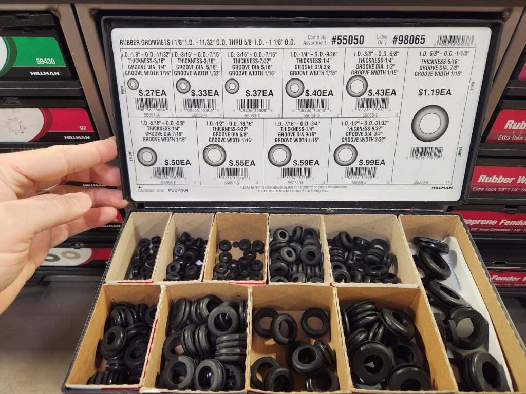 A tray of 10 different assorted sizes of rubber grommets. On the bottom cover of the tray are all the sizing specs and model numbers while several hundred grommets are sorted into small compartments on the bottom of the tray.