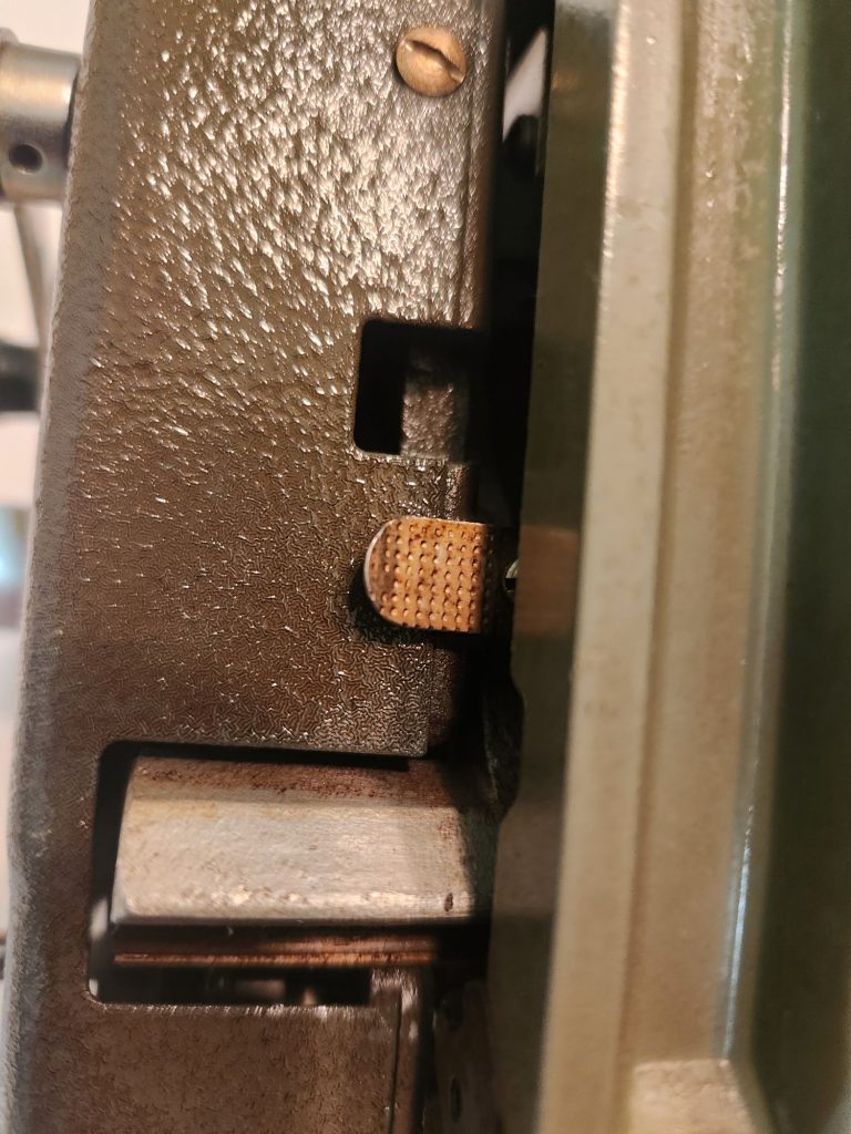 A view of the bottom right side of the carriage. What should have been a green crinkle painted body panel and shiny silver tab at the end of the drawband were coated with a layer of brown nicotine sludge.