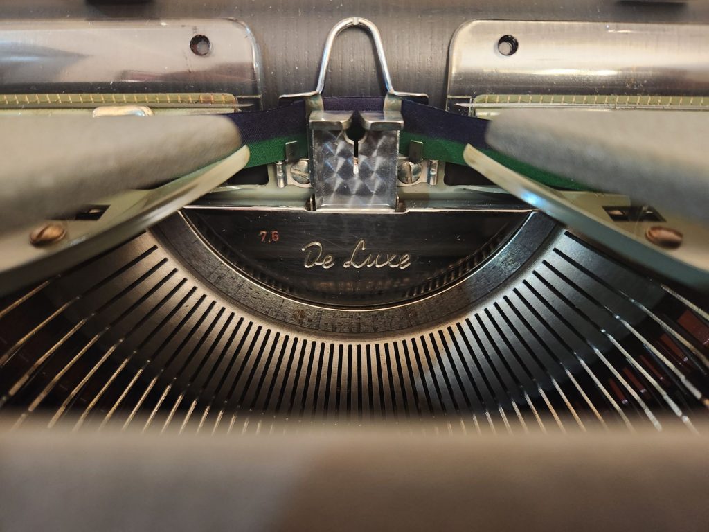 View through the hood of an Olympia SG1 onto the gleaming De Luxe plate in the basket of the typewriter