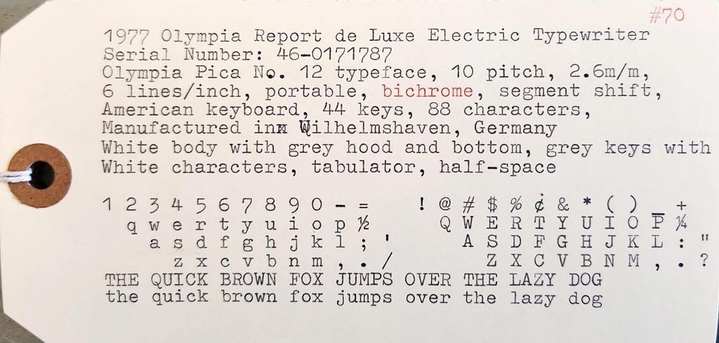 Typesample of a frontal view of 1977 Olympia Report de Luxe typewriter on a yellow manilla tag