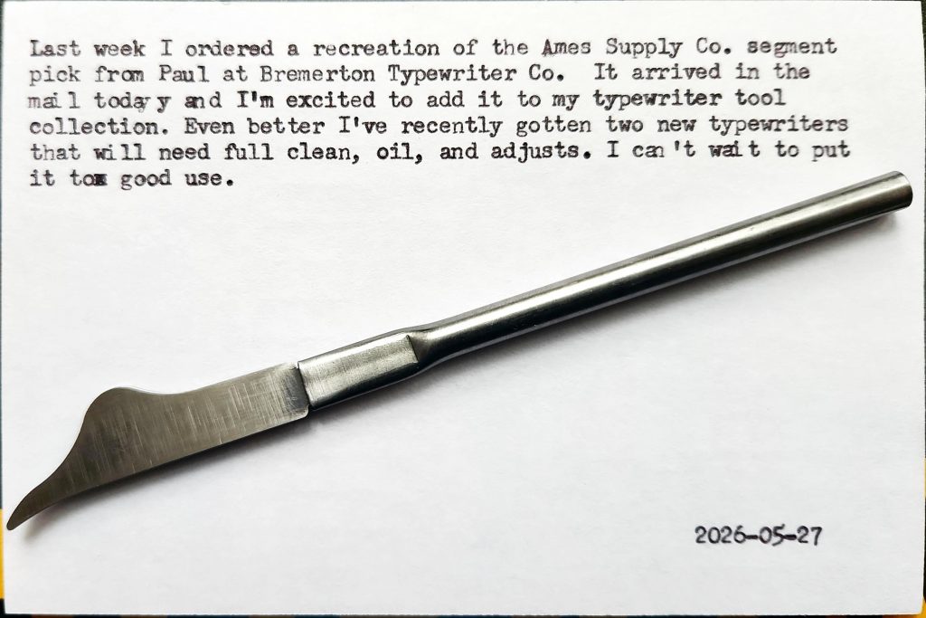 A pen-sized typewriter segment pick with a curved-shaped tip at the end of a thin metal shaft. It sits on top of a typewritten index card that reads: Last week I ordered a recreation of the Ames Supply Co. segment pick from Paul at Bremerton Typewriter Co.  It arrived in the mail today and I'm excited to add it to my typewriter tool collection. Even better, I've recently gotten two new typewriters that will need full clean, oil, and adjusts. I can't wait to put it to good use.