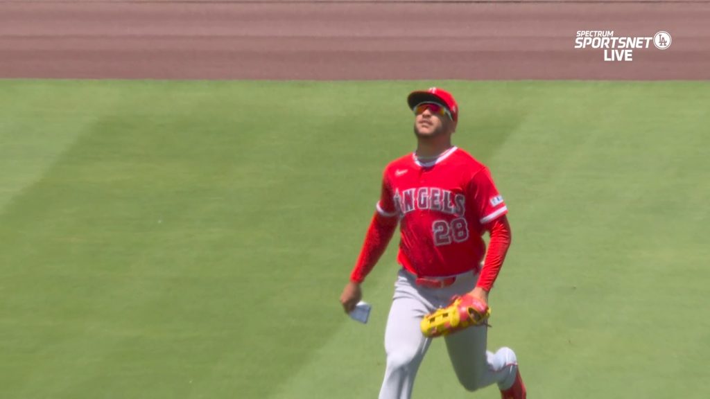 Siri in the Angels' red away uniform with an index card in his right hand tracks a fly ball to center field.
