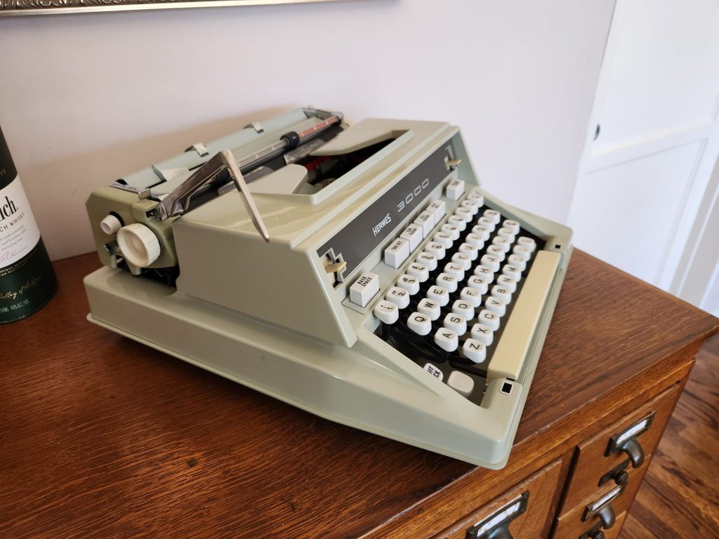 Oblique angle from above the left side of a green Hermes 3000 typewriter