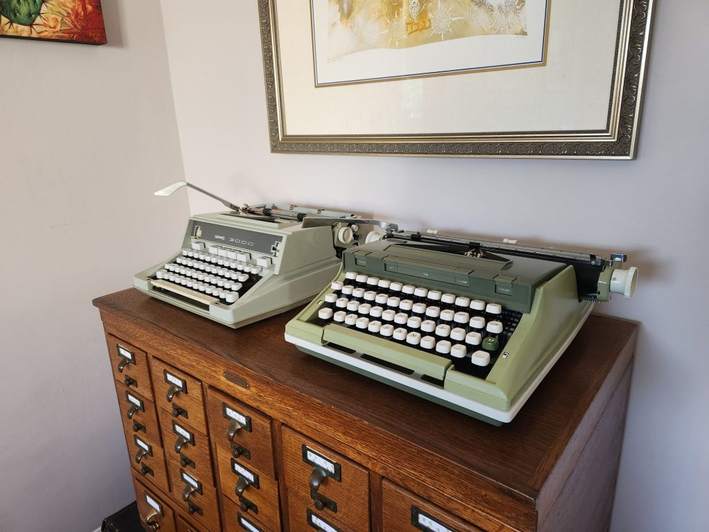 Angle on a Hermes 3000 (further back) and a Sears Newport (foreground) on an oak library card catalog.