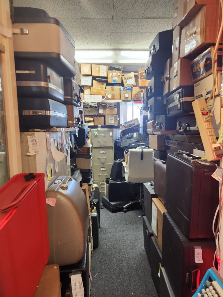 A filing cabinet in the background completely surrounded in the background, middleground, and foreground by hundreds of portable typewriter cases.