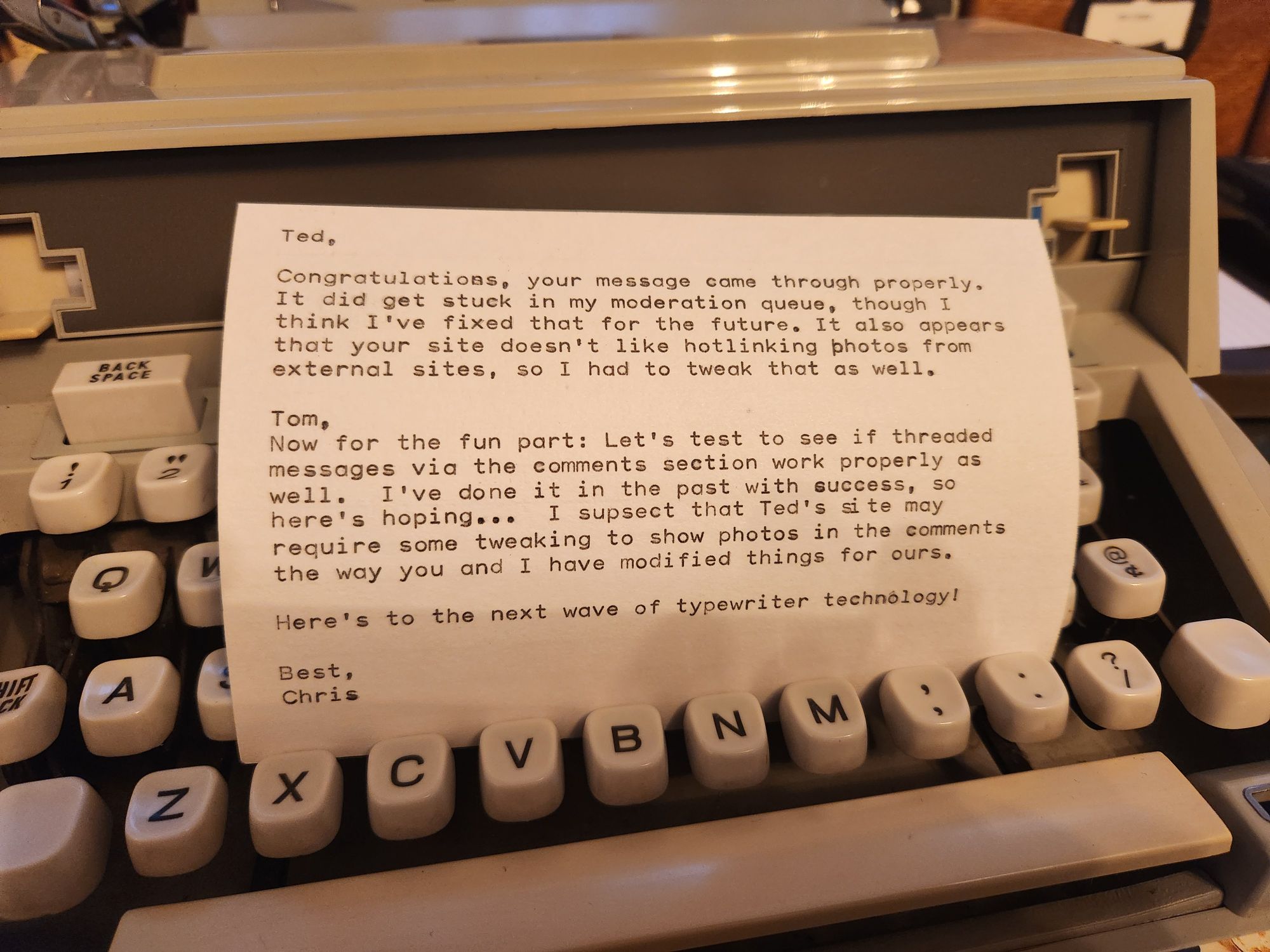 A typed index card sitting in the keys of a light green Hermes 3000 typewriter. It reads: Ted, Congratulations, your message came through properly. It did get stuck in my moderation queue, though I think I've fixed that for the future. It also appears that your site doesn't like hotlinking photos from external sites, so I had to tweak that as well.  Tom, Now for the fun part: Let's test to see if threaded messages via the comments section work properly as well. I've done it in the past with success, so here's hoping... .I suspect that Ted's site may require some tweaking to show photos in comments the way you and I have modified things for ours.  Here's to the next wave of typewriter technology!  Best, Chris